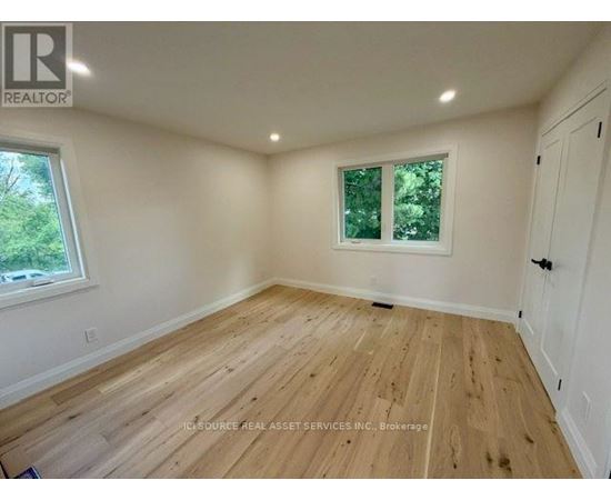 A room with wooden flooring and a window with a view of trees.