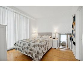 A bedroom with a large bed and a wooden floor.