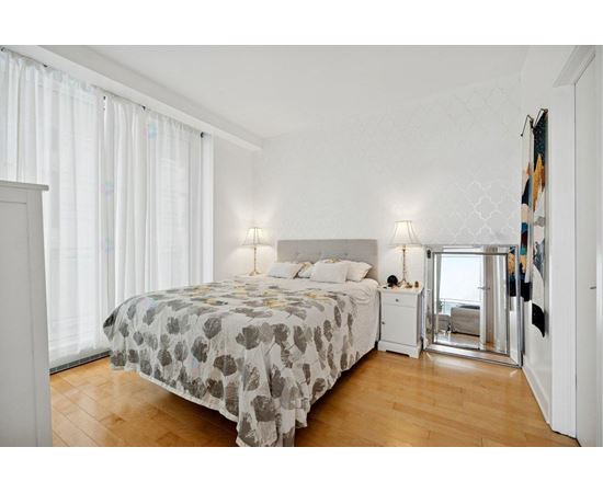 A bedroom with a large bed and a wooden floor.