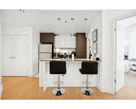 A kitchen with a white counter and black barstools.