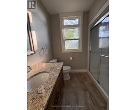 A bathroom with a sink, toilet, and a window.