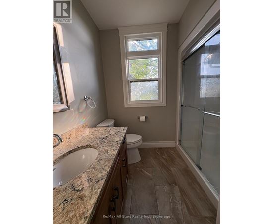 A bathroom with a sink, toilet, and a window.