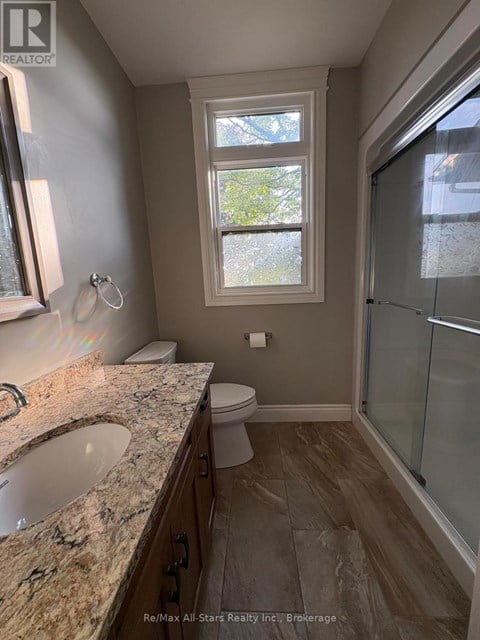 A bathroom with a sink, toilet, and a window.