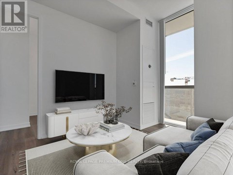 A living room with a white couch and a flat screen TV mounted on the wall.