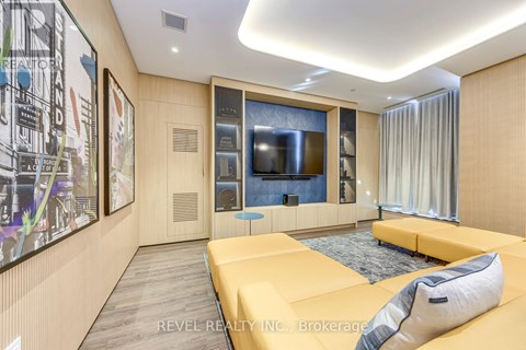A modern living room with a yellow sofa and a large painting on the wall.