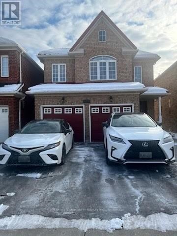 Two white Lexus cars are parked in front of a brick house.