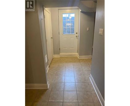 A hallway with a white door and tiled floor.