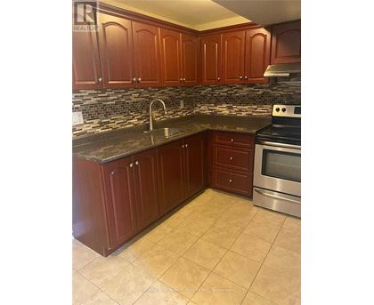 A kitchen with brown cabinets and a tiled backsplash.