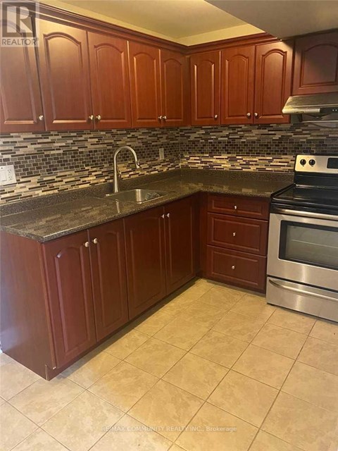 A kitchen with brown cabinets and a tiled backsplash.