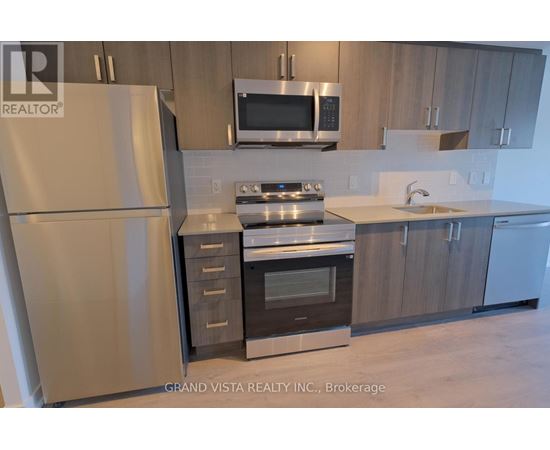 A modern kitchen with a refrigerator, oven, microwave, and sink.