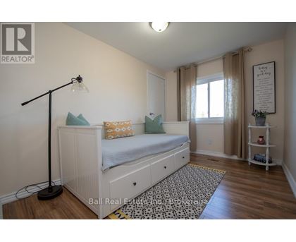 A bedroom with a white bed and a black floor lamp.
