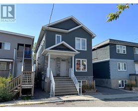 A house with a grey front yard and a sign that says REALTOR.