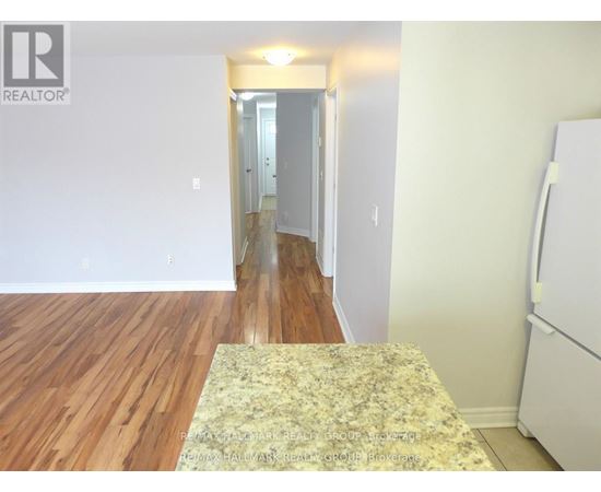 A bedroom with a rug on the floor and a white refrigerator on the right.