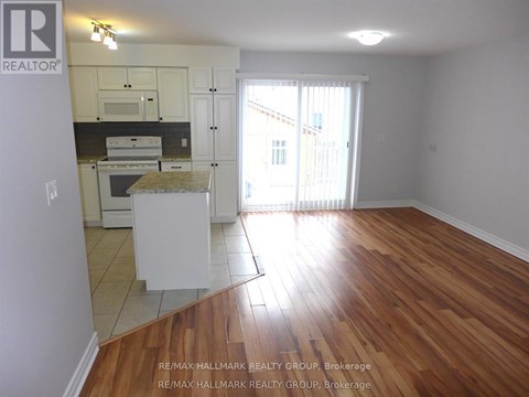 A kitchen with white cabinets and a wooden floor.