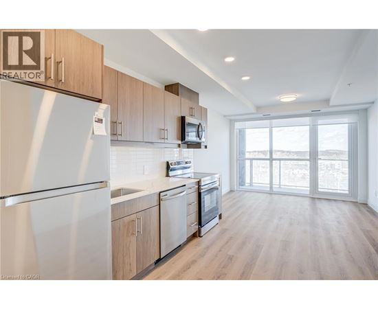 A well-lit kitchen with wooden cabinets and a refrigerator.
