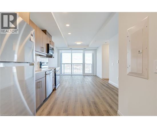 A modern kitchen with wooden floors and stainless steel appliances.