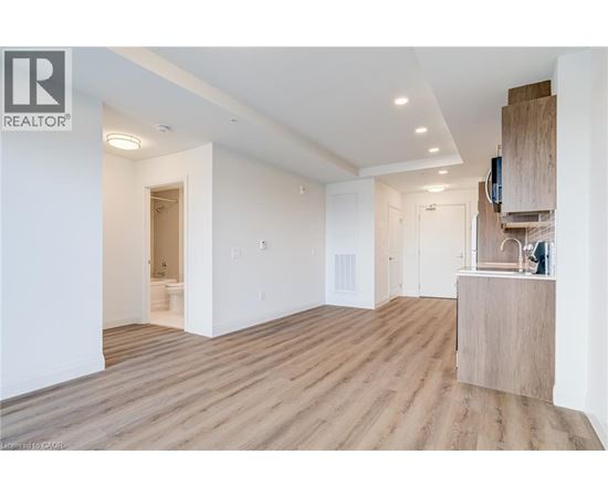 A spacious room with wooden flooring and white walls.