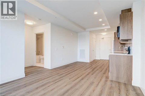 A spacious room with wooden flooring and white walls.
