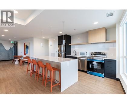 A modern kitchen with a bar area and orange chairs.