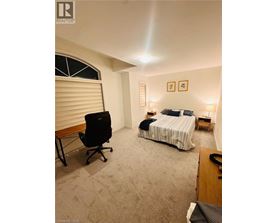 A bedroom with a bed, chair, and two lamps.