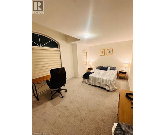 A bedroom with a bed, chair, and two lamps.