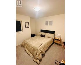 A bedroom with a bed, nightstand, and two pictures on the wall.