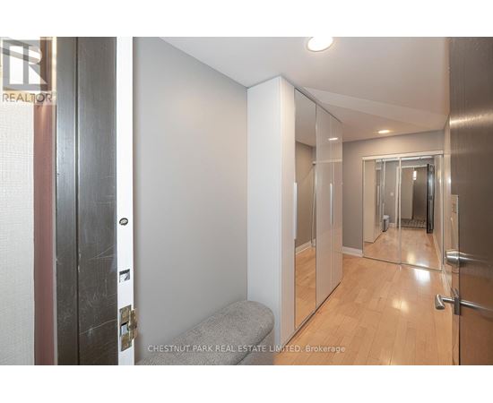 A hallway with a bench and a mirrored door.
