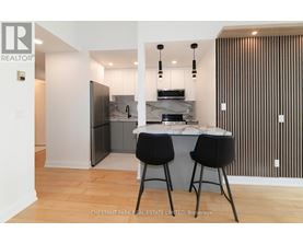 A modern kitchen with a bar stool and a fridge.