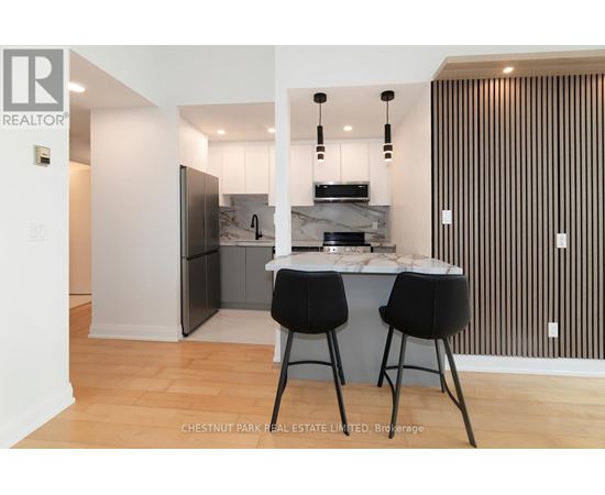 A modern kitchen with a bar stool and a fridge.