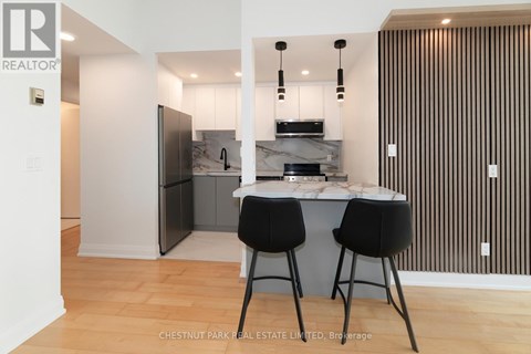 A modern kitchen with a bar stool and a fridge.