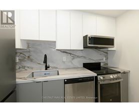 A kitchen with a marble backsplash and white cabinets.