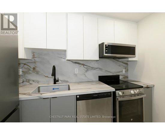 A kitchen with a marble backsplash and white cabinets.