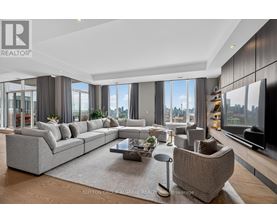 A modern living room with a large grey sofa and a coffee table in the center.