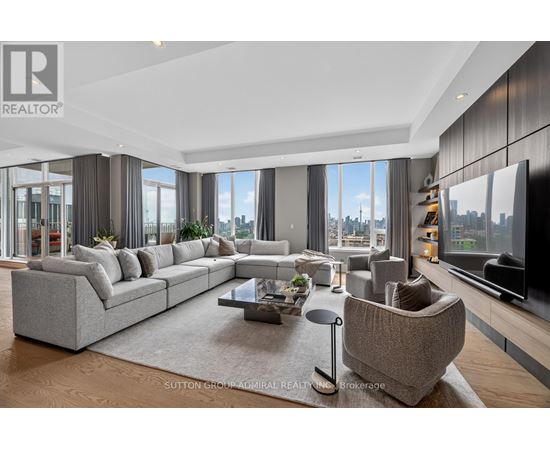 A modern living room with a large grey sofa and a coffee table in the center.