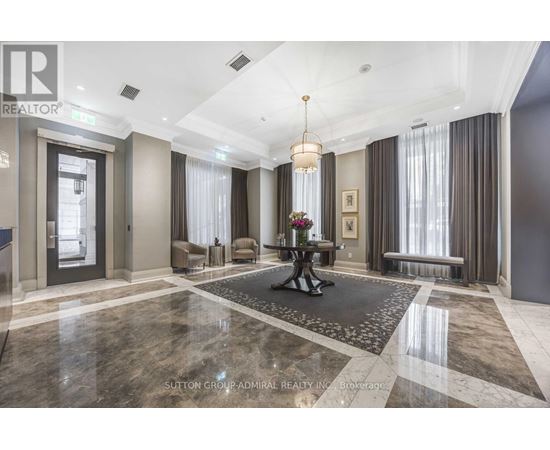 A well-lit, spacious lobby with a marble floor and a chandelier hanging from the ceiling.
