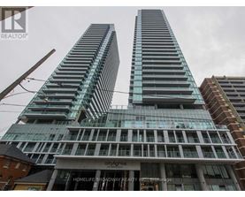 Two tall buildings with glass windows and balconies are in front of a cloudy sky.