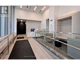 A hallway with a black carpet and glass railings.
