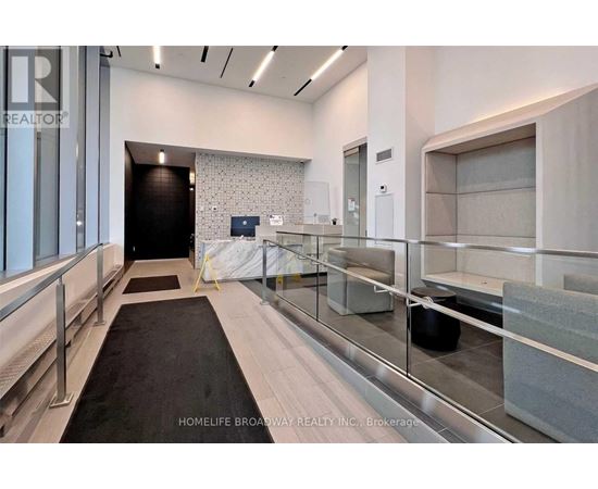 A hallway with a black carpet and glass railings.