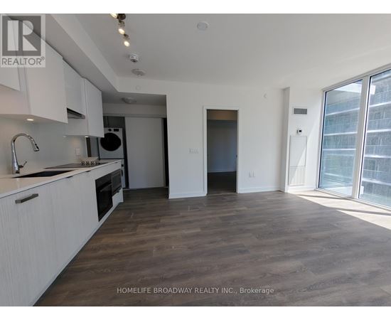 A spacious kitchen with white cabinets and a wooden floor.