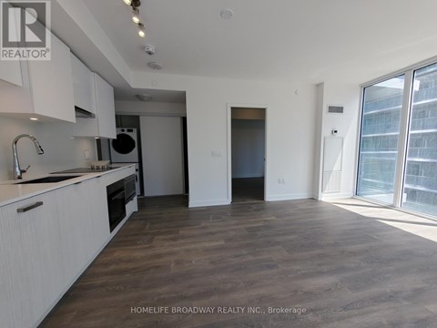 A spacious kitchen with white cabinets and a wooden floor.