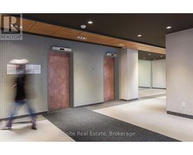A hallway with a person walking in the background and a sign that says "Innite Real Estate Brokerage".