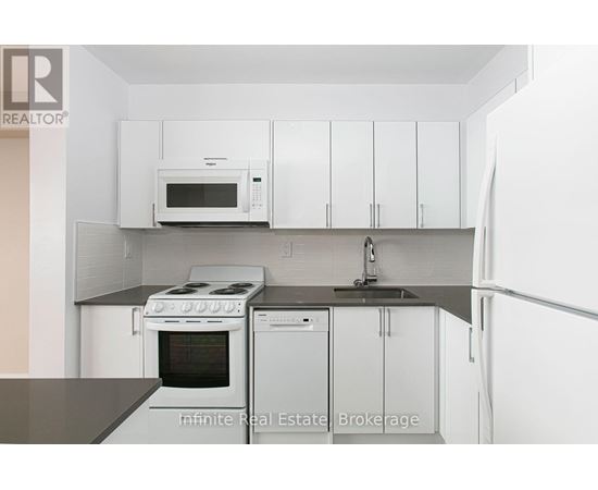 A kitchen with white cabinets and a black counter top.