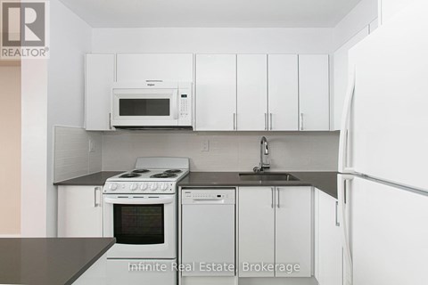 A kitchen with white cabinets and a black counter top.