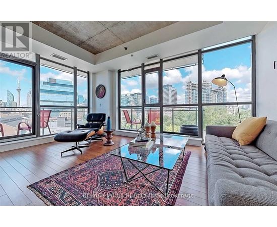 A living room with a grey couch, a glass coffee table, and a large window with a view of the city.