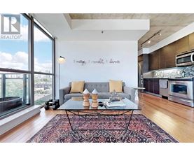 A living room with a grey couch and a coffee table in front of a window.