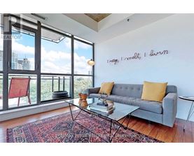 A living room with a grey couch and a glass table.