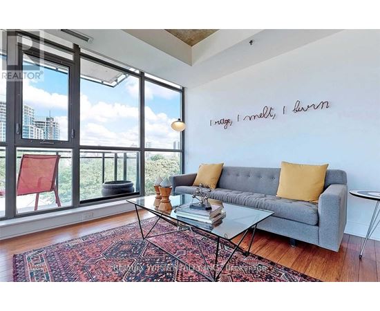 A living room with a grey couch and a glass table.