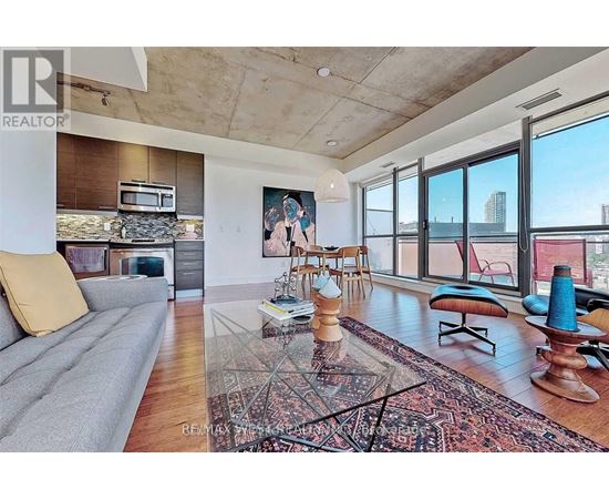 A living room with a grey sofa and a rug in the middle.