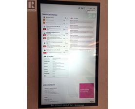A monitor displays a transit schedule with bus numbers and destinations.
