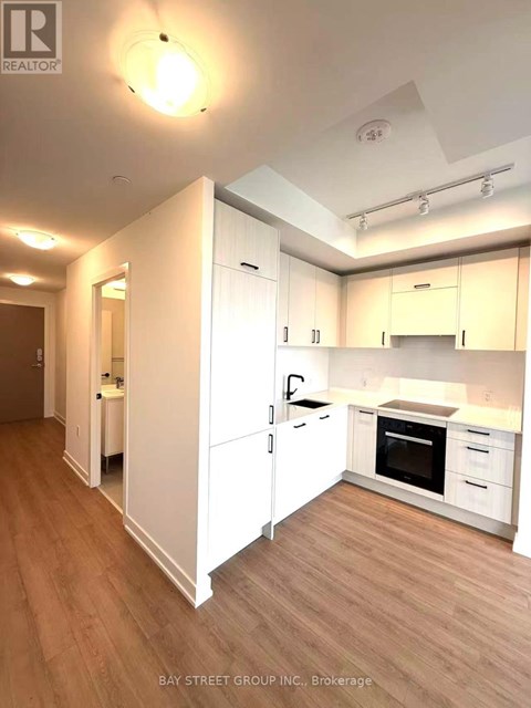 A kitchen with white cabinets and a wooden floor.